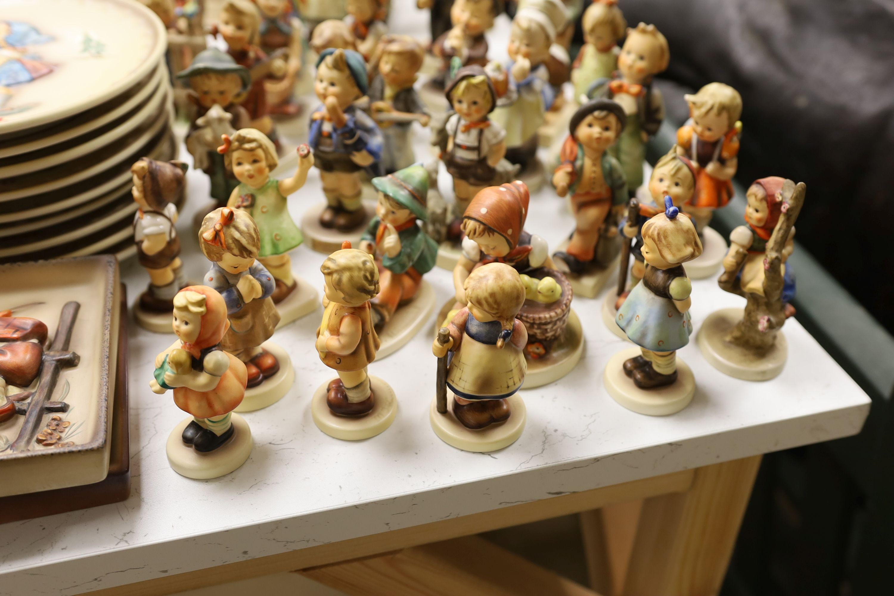 A large collection of Hummel pottery figures, approximately 70 including skier and two similar plaques, some with boxes.